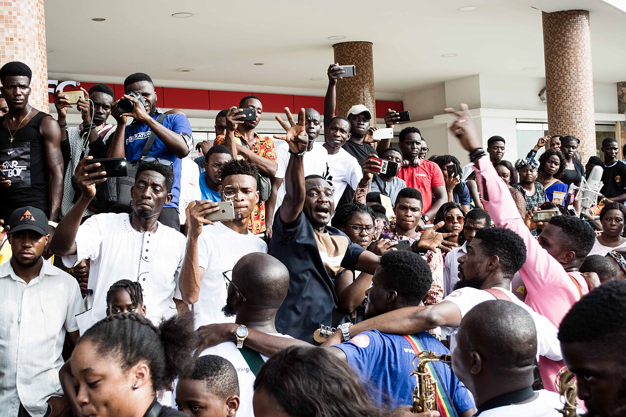 A crowd at a Lagos mall cheering and filming on their phones.