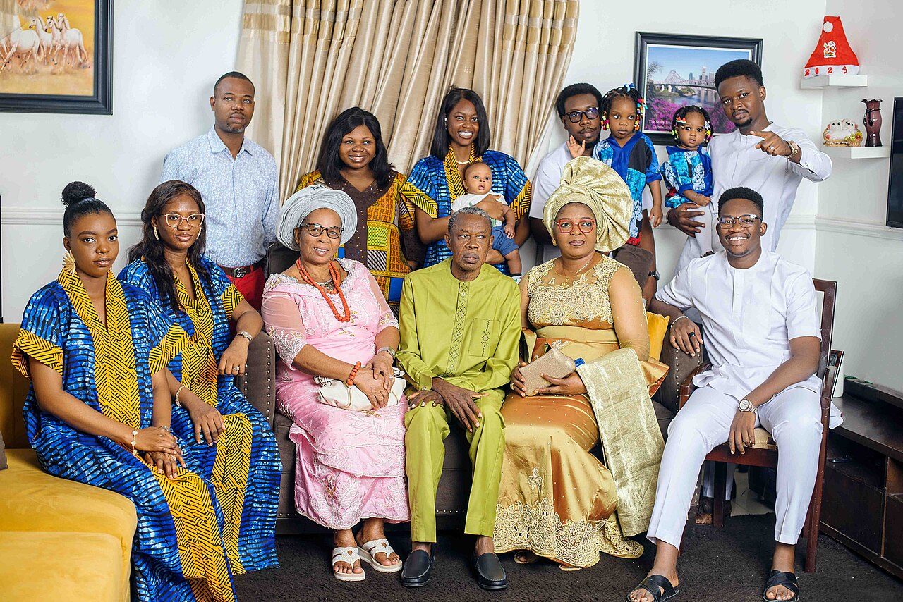 A large family in matching traditional outfits posing together at home.