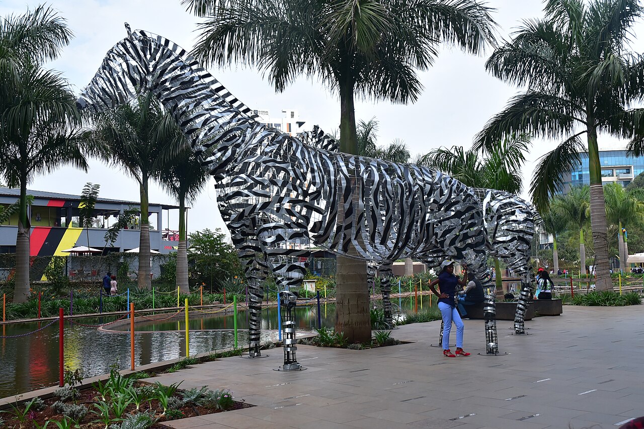 A shopper at Two Rivers Mall in Nairobi beside a giant steel zebra sculpture.